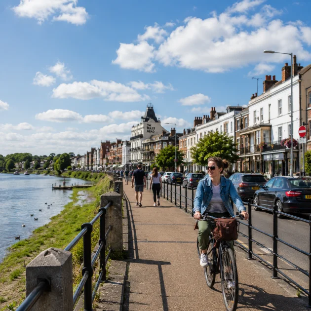 Cyclist travelling along the River Thames promenade in Barnes on a sunny day