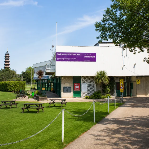 Entrance to Old Deer Park Sports Ground in Richmond, London, showing the sports pavilion, landscaped grounds, and pedestrian access near MG Rehab.