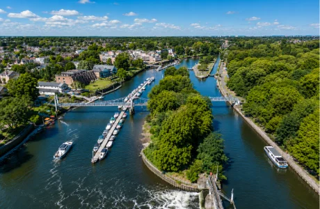 Aerial view of Teddington Lock on the River Thames in Teddington, London, showing the lock, footbridges, marina, and surrounding green spaces.